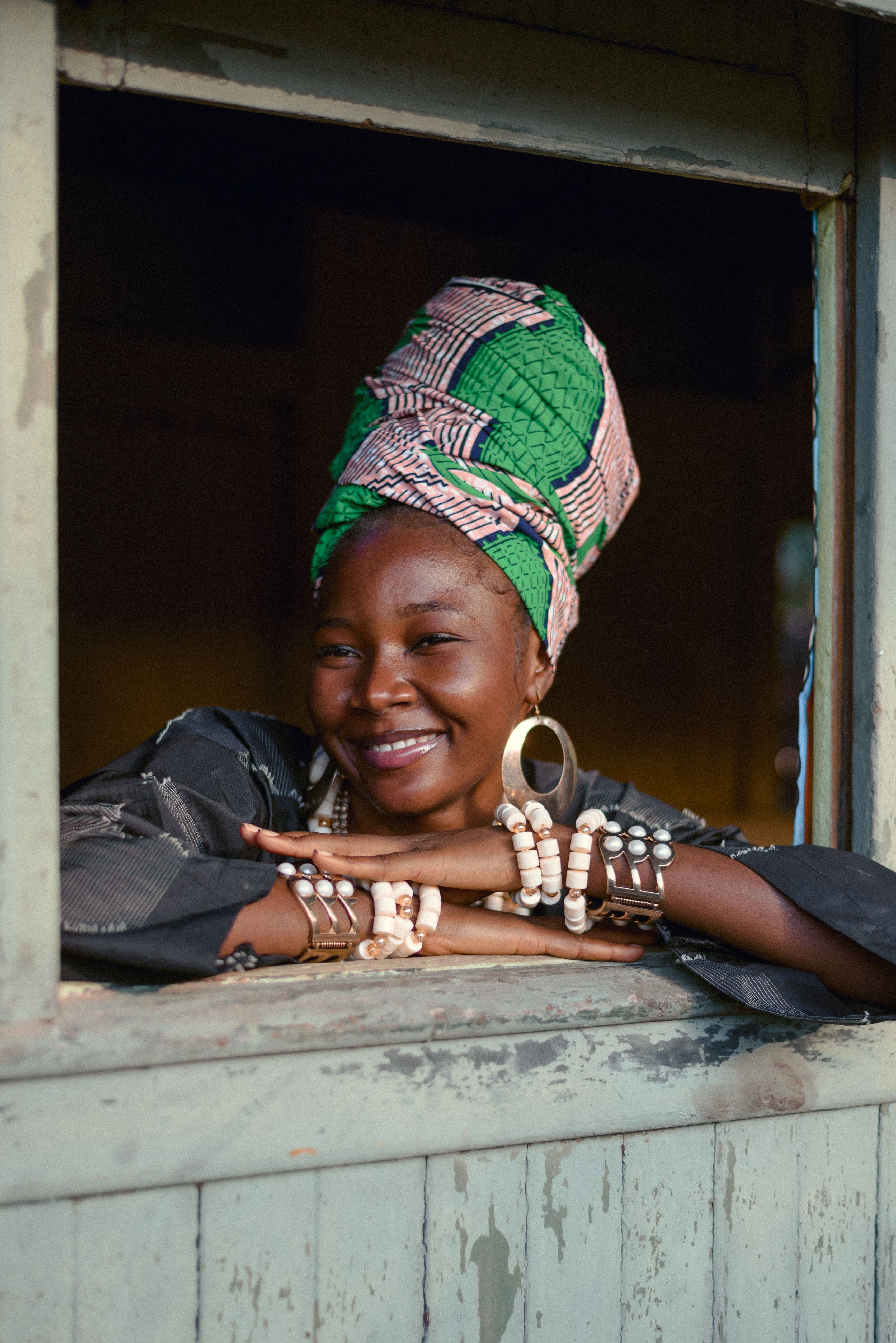 A smiling woman wearing a green patterned headwrap